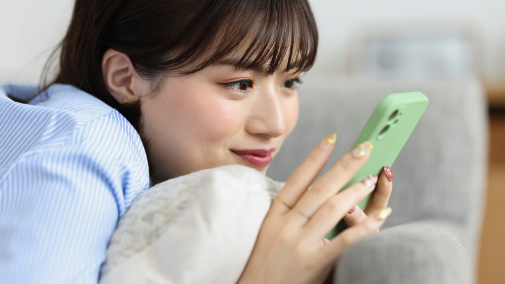自宅で一人、ノートやスマートフォンに気持ちを書き出している日本人女性。