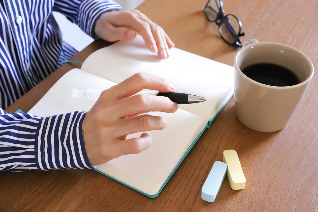 日本人の若い人物が、ノートや付箋に自分の経験を書き出している手元のアップ、またはデスクで作業する様子。