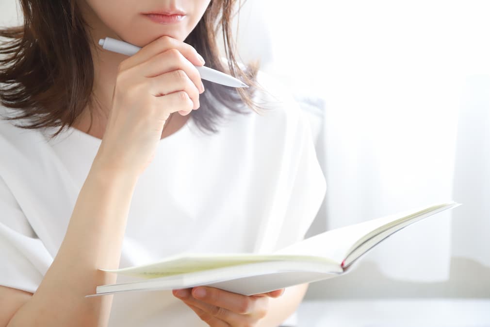 転職について考えながら、ノートや手帳に考えを書き出している30代前後の会社員。
